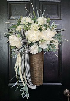 a basket filled with white flowers sitting on top of a door