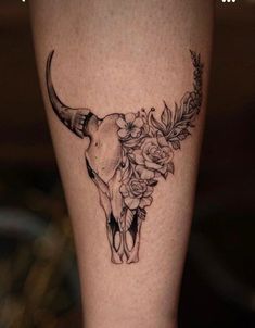 a cow skull with flowers on it's side and an arrow in the middle