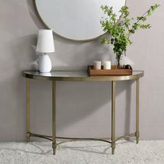 a round mirror sitting on top of a table next to a white vase and candle