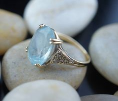 This is the perfect option for those who like cool, unique jewelry and the luxury, shine of yellow gold. This ring is well made, cute and/or elegant in design, and very desirable. Vintage ring decorated with the aquamarine like stone in the center and from the side is decorated with little diamonds . The 3 diamonds are missing. This ring stands out by itself or it is beautiful stacked with others rings. ♥ Age/era: 1980s - 1990s. ♥ The ring is a hallmark. 14K F.M. Franklin Mint. ♥ The ring's size Oval Aquamarine Diamond Ring Gift, Oval Aquamarine Diamond Ring As Gift, Blue Diamond Ring With 14k Gold Accents, Gold Aquamarine Diamond Ring, Gold Aquamarine Diamond Ring With Gemstones, Light Blue Diamond Ring Fine Jewelry, Light Blue Diamond Ring In Fine Jewelry Style, Gold Diamond Ring With Aquamarine, Yellow Gold Blue Topaz Diamond Ring As A Gift