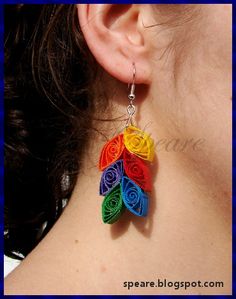 a woman wearing earrings made out of multicolored paper