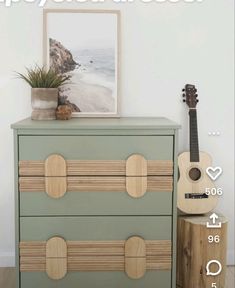 a green dresser with two drawers and a guitar on top of it next to a potted plant