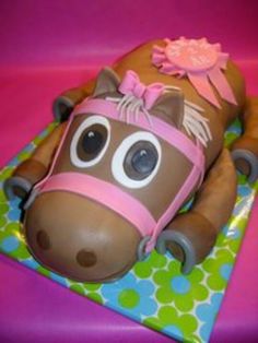 a cake shaped like a horse laying on top of a green and pink table cloth