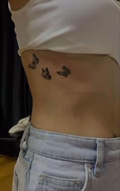 a woman's stomach with three butterflies on her left side and the bottom part of her lower back