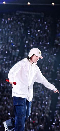 a man in white jacket and hat on skateboard doing a trick at a show