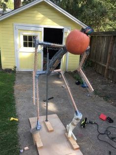 an orange ball is in the air on top of a piece of wood near a small yellow house