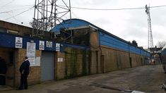 two men are standing in front of an industrial building