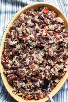 a bowl filled with rice and beans on top of a striped table cloth next to a spoon