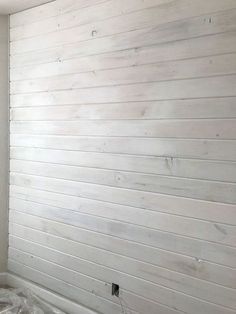 an unfinished room with white paint on the walls and wood paneling in the corner