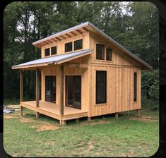 a small wooden house sitting on top of a lush green field with trees in the background