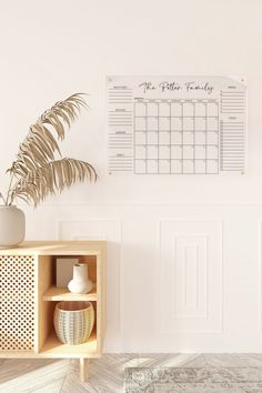 a white wall with a calendar on it next to a potted plant and vase