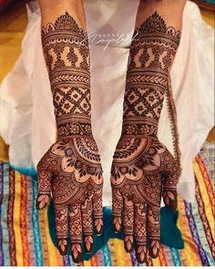 a woman's hands with henna tattoos on her arm and hand, showing the intricate