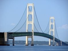 a large bridge spanning over the water with a boat in it's foreground