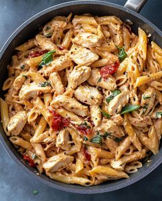 pasta with chicken and tomatoes in a skillet on a blue table top view from above