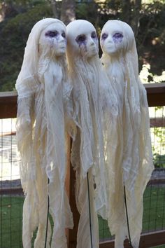 three white dolls with long hair and purple eyes are standing in front of a fence