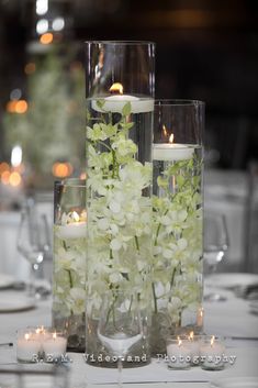 white flowers and candles are arranged in glass vases