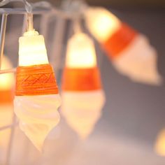 several orange and white lights hanging from a wire