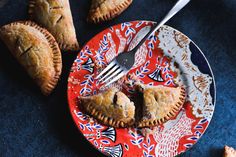 two pieces of pie on a red plate with a fork and knife next to it