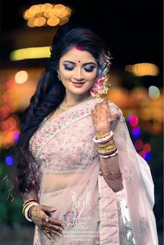 a woman wearing a white sari and holding a flower in her hand