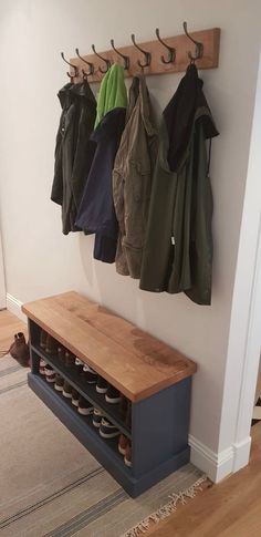 a coat rack with shoes and coats hanging from it's hooks on the wall