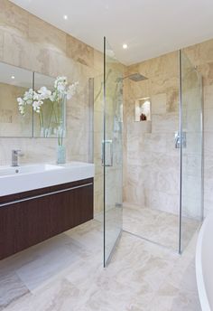 a bathroom with a sink, shower and large mirror on the wall next to it