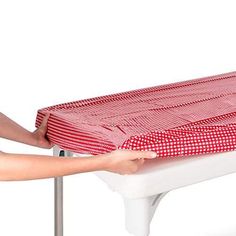 a red and white checkered table cloth being held by a person's hand