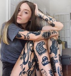 a woman sitting on the floor with her legs covered in tattoos and leggings