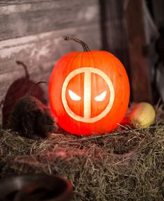 a pumpkin carved to look like the letter t is sitting on hay with other pumpkins around it