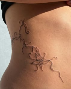 a woman's stomach with an intricate tattoo design on the bottom part of her belly