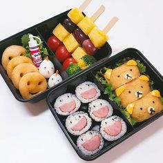 two black trays filled with different types of food