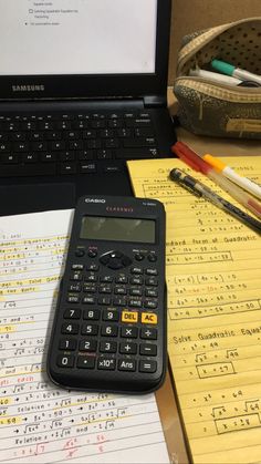 a calculator sitting on top of a desk next to an open laptop computer