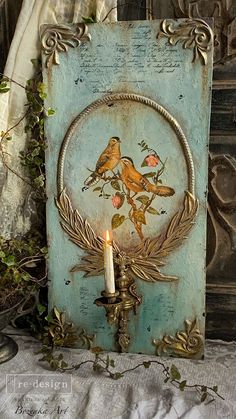 a candle that is sitting in front of a plaque with two birds and flowers on it