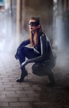 a woman dressed as catwoman crouching down on the ground with her hands in her pockets