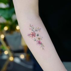 a woman's arm with a flower tattoo on the left side of her arm