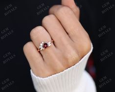 a woman's hand with a red and white diamond ring on top of it