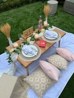 a table set up with plates and place settings for an outdoor dinner on the grass