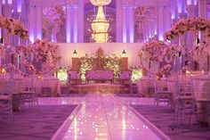 an elaborately decorated ballroom with purple lighting and floral centerpieces on the dance floor