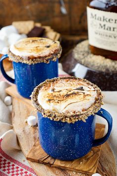 two blue mugs filled with hot chocolate and whipped cream