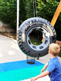 a young boy is playing with a tire swing