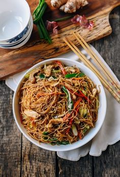 a bowl filled with noodles and vegetables next to chopsticks