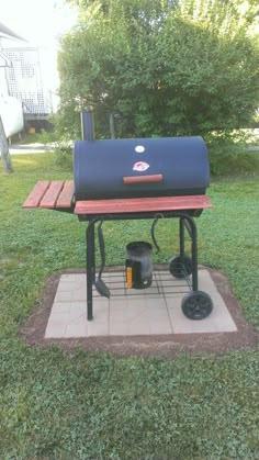 an outdoor bbq grill in the middle of a yard with grass and trees behind it