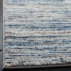 an area rug with blue and grey stripes on the top, in front of a black floor