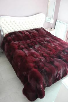 a bed with a red fur comforter on top of it