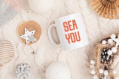 a white coffee mug with the words sea you on it next to other items such as seashells and starfish