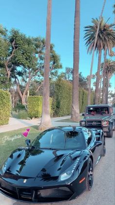 a black sports car is parked on the side of the road next to some palm trees