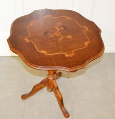 a small wooden table with an ornate design on it's top and two legs