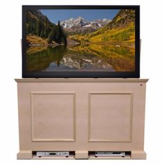 a flat screen tv sitting on top of a wooden cabinet next to a mountain lake