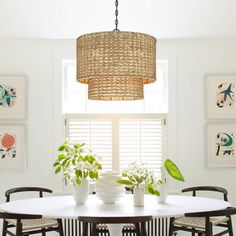 a dining room table and chairs with plants on the table in front of them under a chandelier