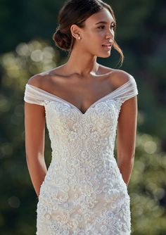 a woman in a white wedding dress is looking back at the camera with her hand on her hip