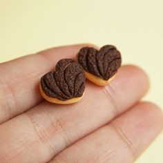 two heart shaped cookies sitting on top of a person's hand